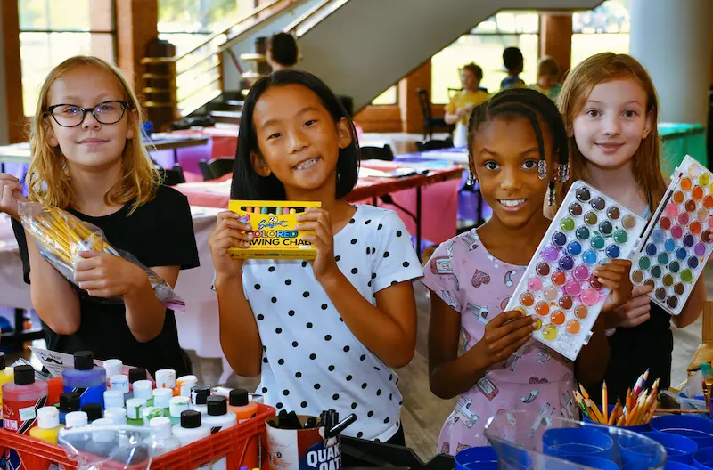 Children holding up art supplies